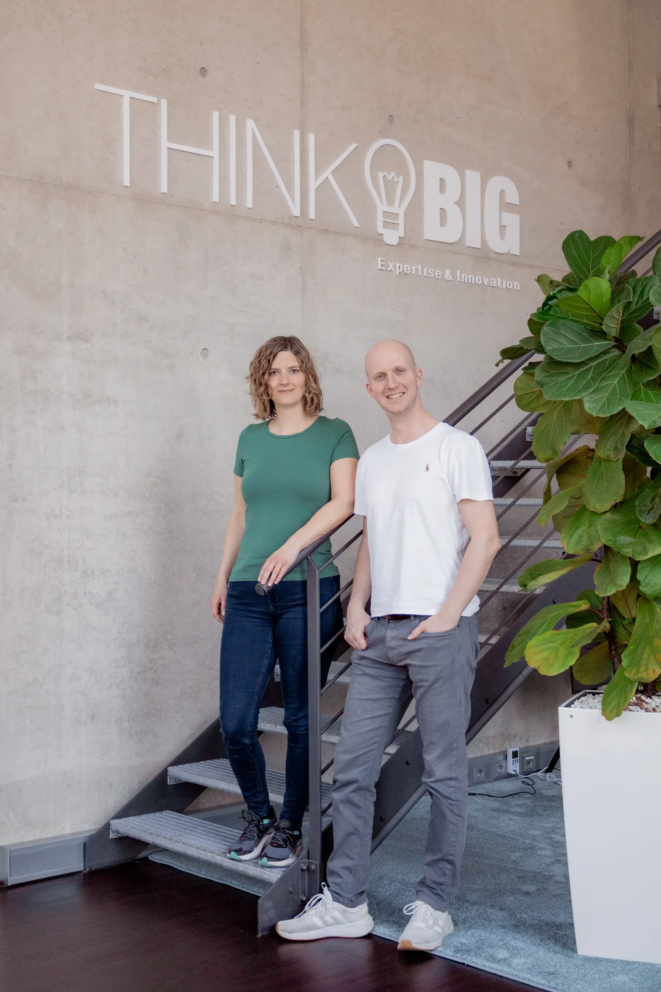 Zwei Kollegen vor dem "Think Big"-Schriftzug der KMH